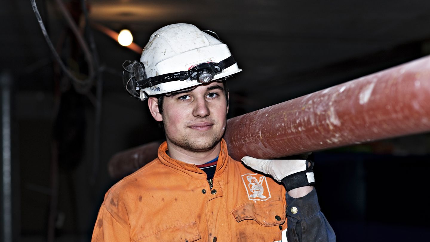 Bildet viser en ung mann som løfter et rør på ryggen.